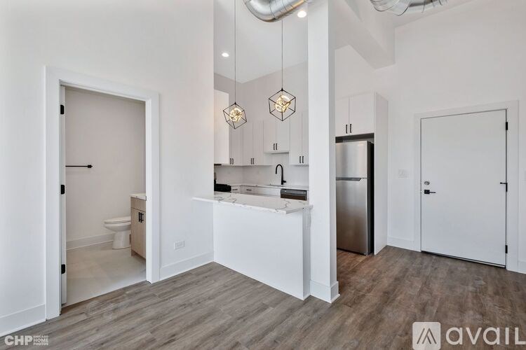 A modern kitchen with white cabinets and a wooden floor.