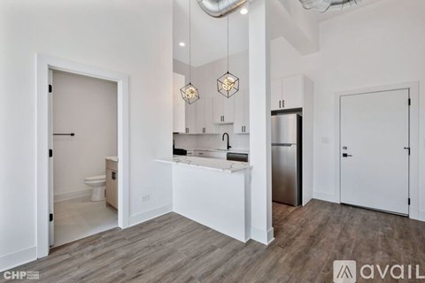 A modern kitchen with white cabinets and a wooden floor.