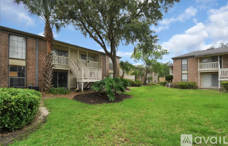 A tree in a grassy area in front of apartment buildings.