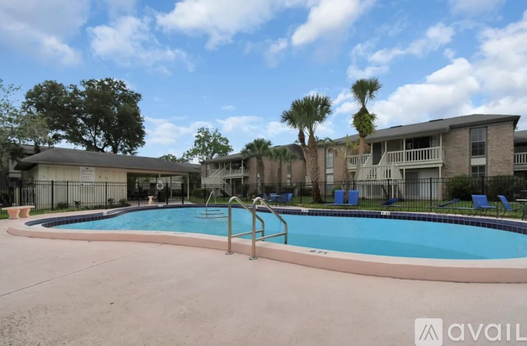 A pool surrounded by a concrete patio and a building in the background.