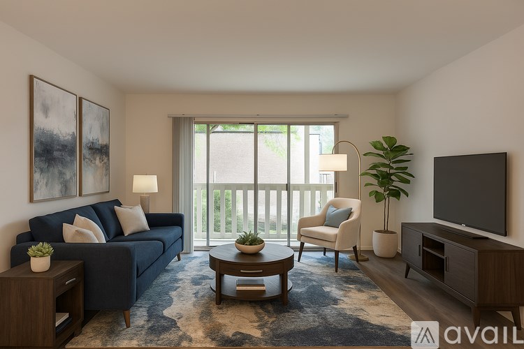 A living room with a blue couch, a chair, a coffee table, and a flat screen TV.