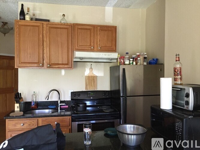 A kitchen with wooden cabinets and a black refrigerator.