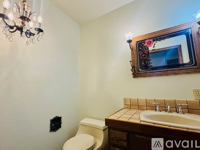 A bathroom with a toilet, sink, and a chandelier.