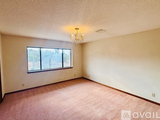 A room with a chandelier, carpet, and a window.