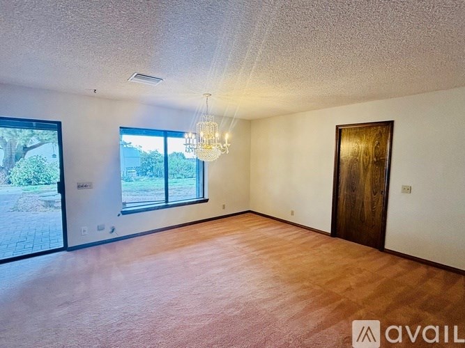 A room with a wooden floor, a chandelier, and a door.