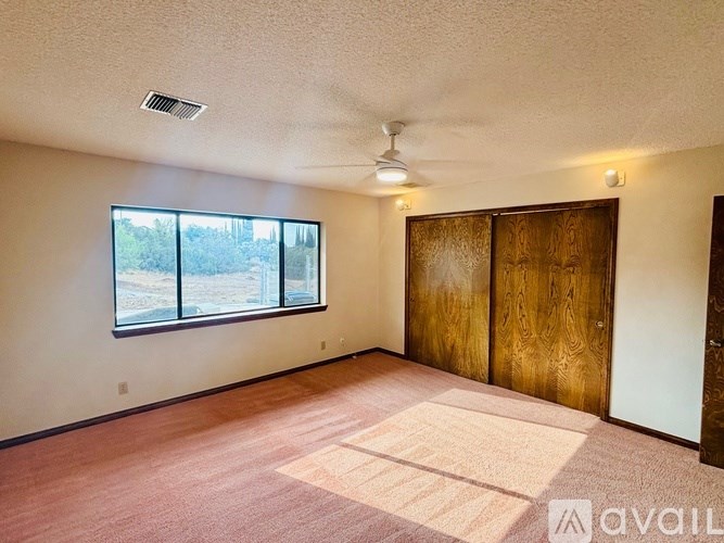 A room with a ceiling fan and a large window.
