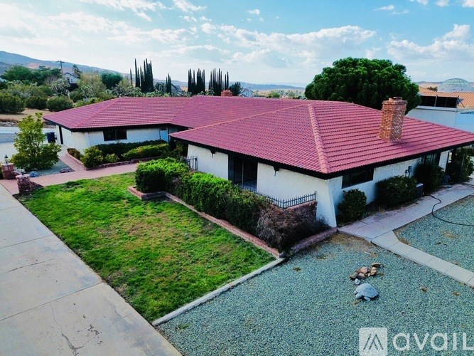 A house with a red roof and white walls is surrounded by a garden.