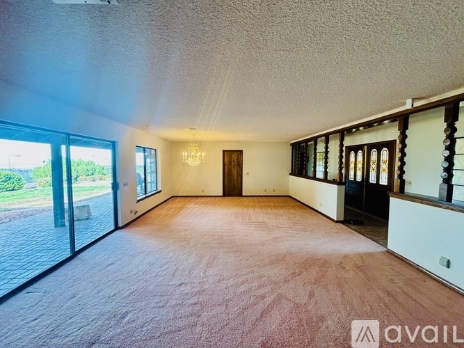 A spacious room with a wooden floor and a chandelier hanging from the ceiling.