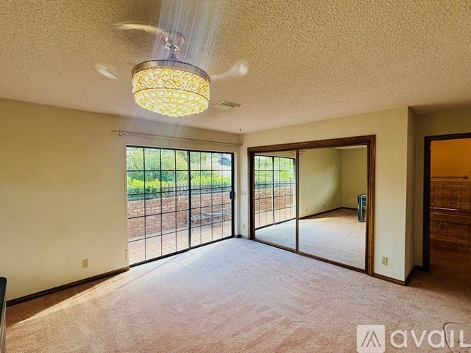 A room with a carpeted floor and a chandelier hanging from the ceiling.