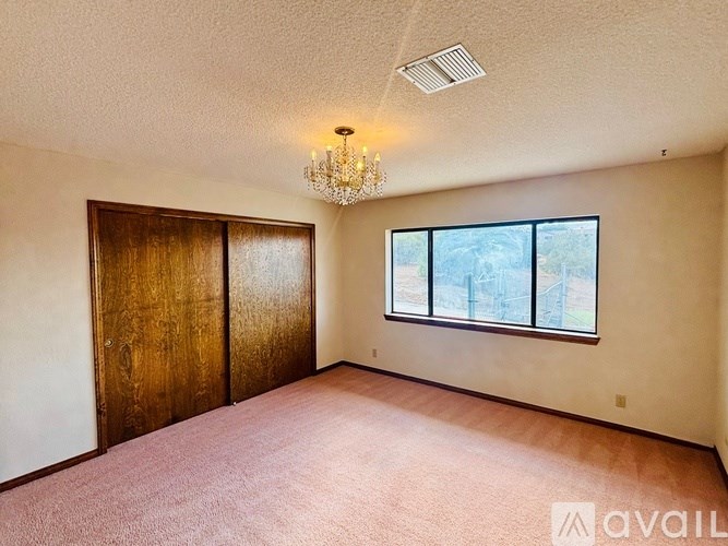 A room with a chandelier, two doors, and a window.