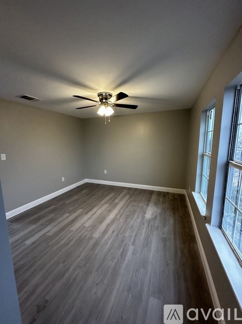 A room with a ceiling fan and wooden flooring.