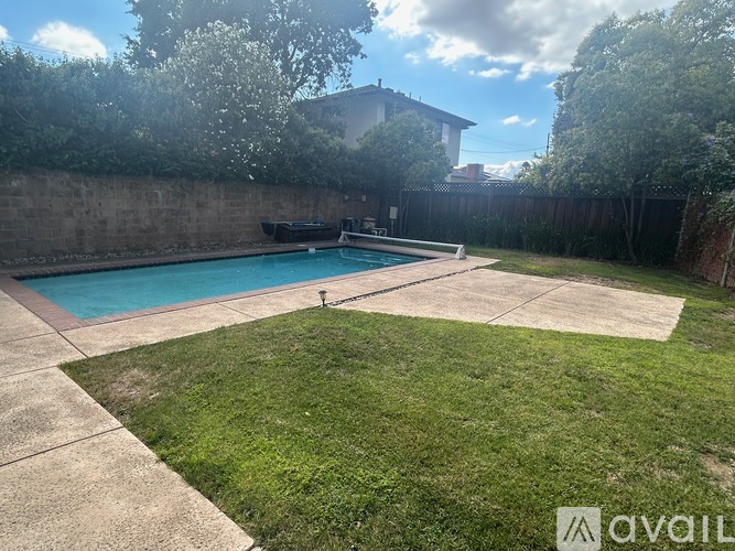 A backyard with a pool and a concrete patio.