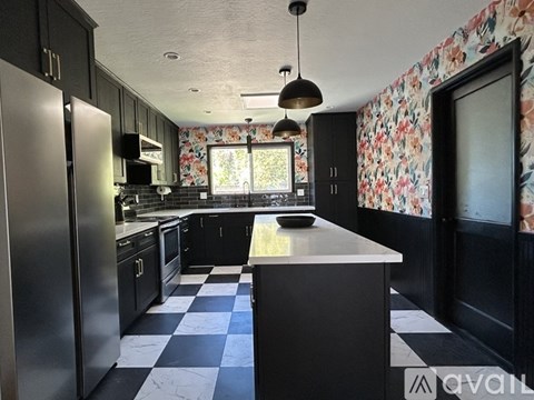 A kitchen with black cabinets and a checkered floor.