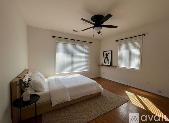 A bedroom with a bed, a ceiling fan, and a window with blinds.