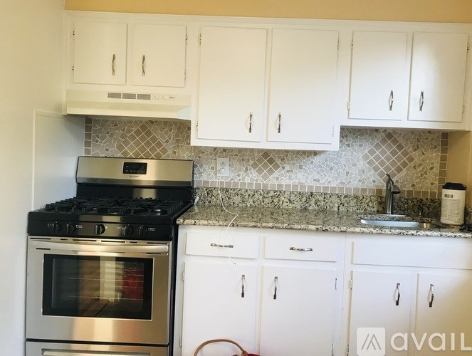 A kitchen with white cabinets and a stove top oven.