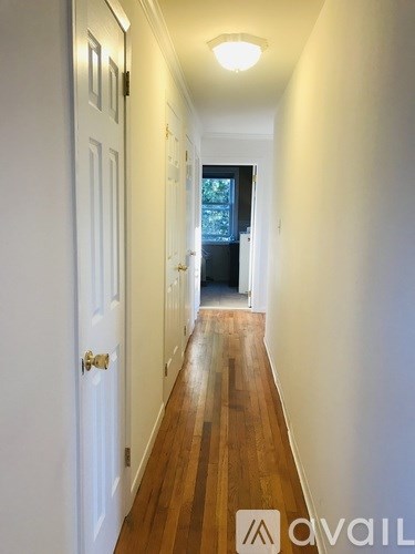 A long hallway with white walls and wood floors.