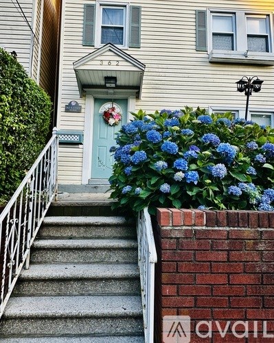 A house numbered 362 with a blue door and a flower bed in front.