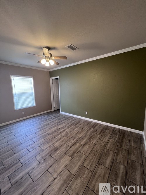 A room with a ceiling fan and wooden flooring.