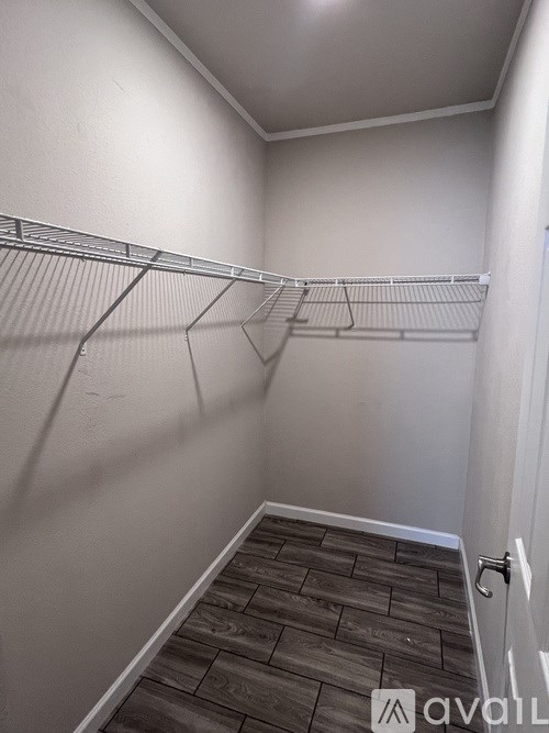 A small, empty room with a wooden floor and a metal rack on the wall.
