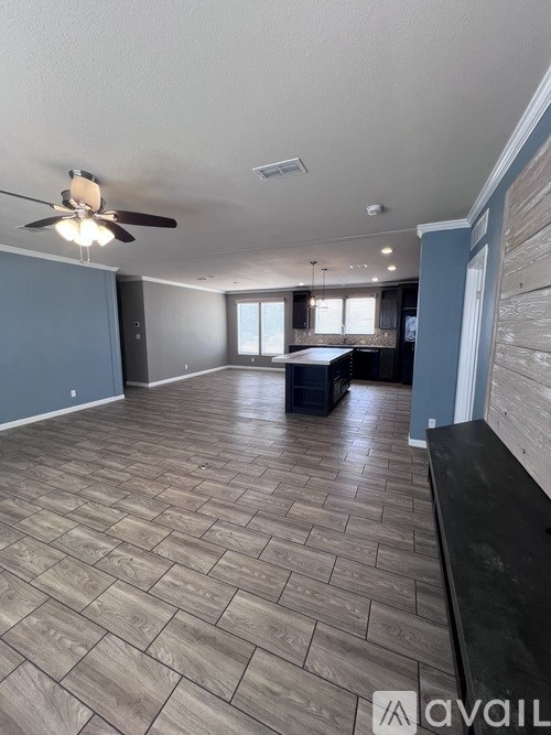 A spacious room with wooden flooring and a ceiling fan.