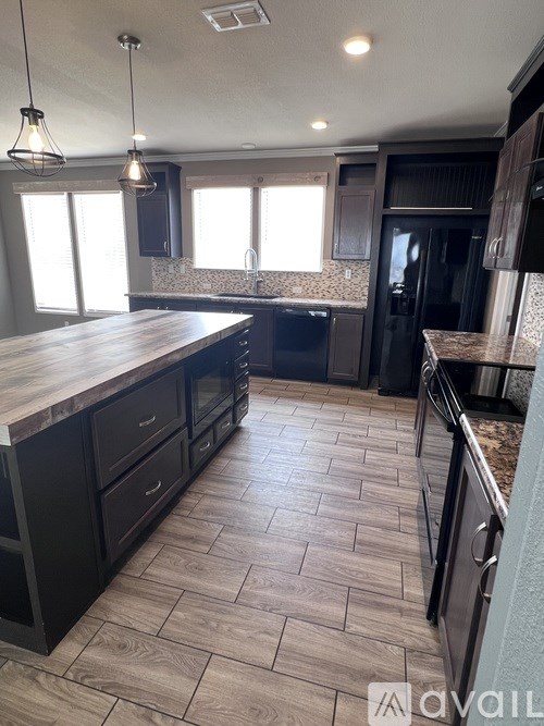 A kitchen with a wooden countertop and black cabinets.