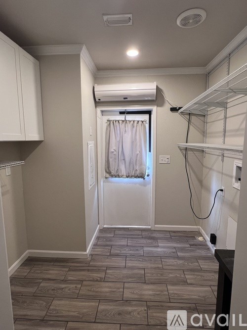 A small, empty room with a window and a wooden floor.