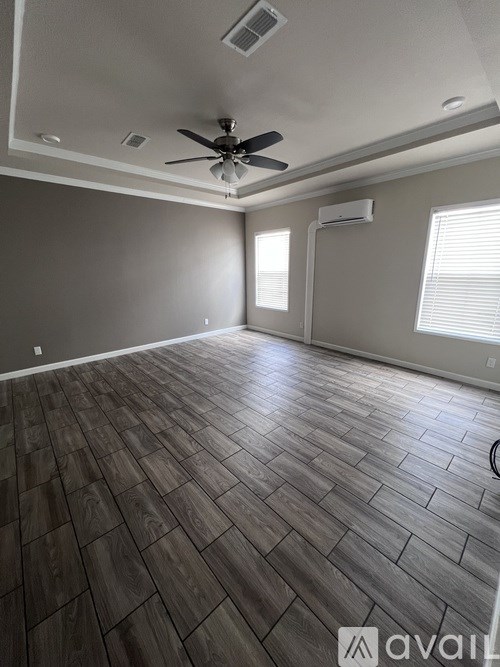 A room with a ceiling fan and wooden flooring.