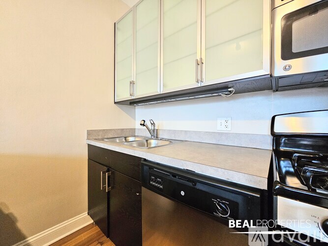 A kitchen with a black dishwasher and a white countertop.