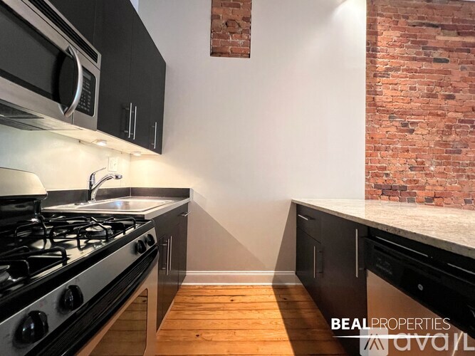 A spacious room with wooden flooring and a fireplace.