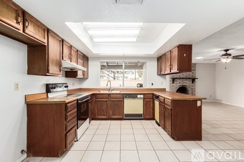 A kitchen with brown cabinets and a white tile floor.