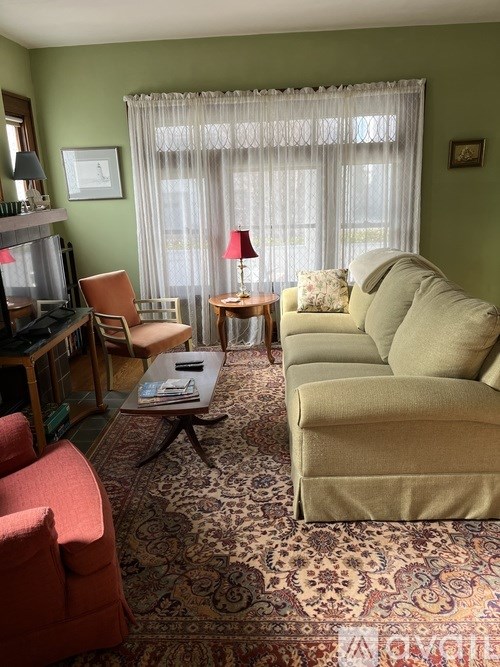 A living room with a rug, a couch, a chair, a coffee table, and a television.