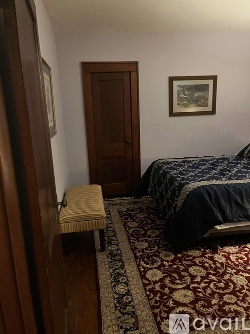 A bedroom with a bed, a bench, and a rug.
