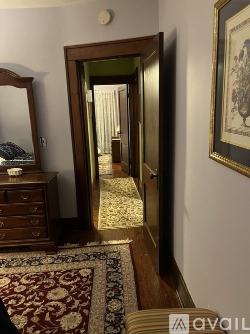 A hallway with a rug and a framed picture on the wall.