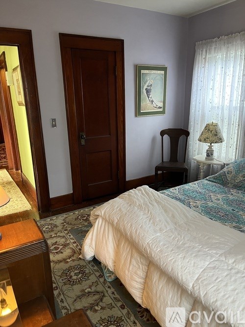 A bedroom with a bed, a nightstand, a lamp, and a painting on the wall.