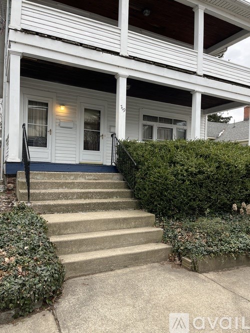 A white house with a porch and stairs leading to the front door.