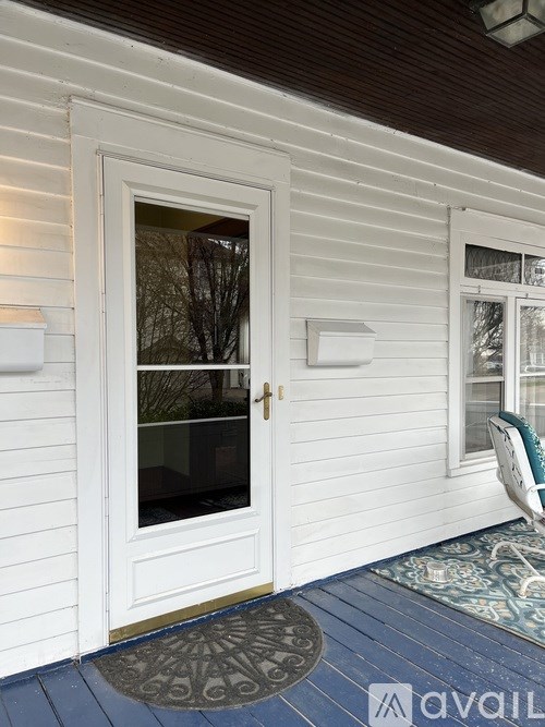 A white door with a glass window is on the left side of a wooden house.