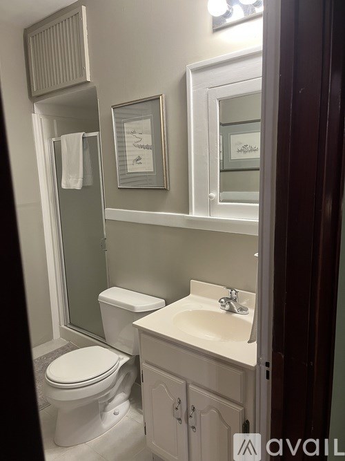 A bathroom with a toilet, sink, and mirror.