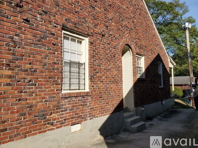 A red brick house with a white window and a white door.