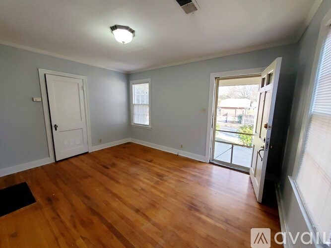 A room with wooden floors and a sliding glass door leading to a balcony.