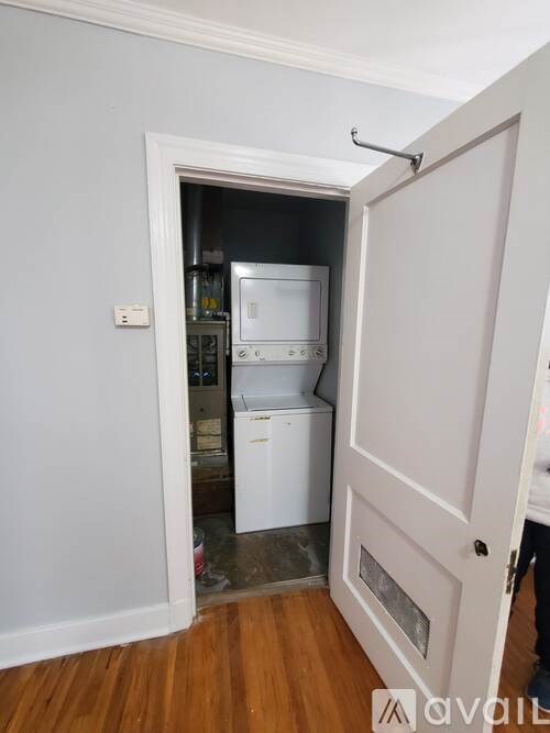 A white door is open to a small kitchen with a washing machine and dishwasher.