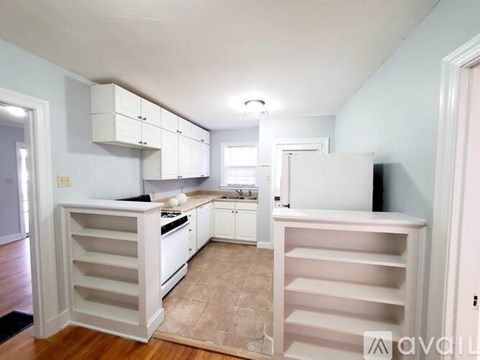 A kitchen with white cabinets and a wooden floor.