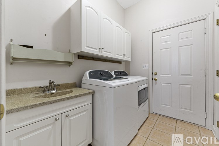 A white kitchen with a sink, stove, and cabinets.