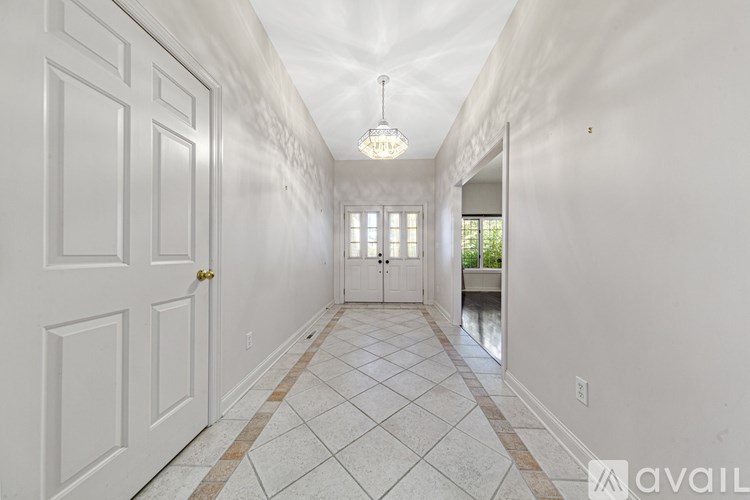 A long hallway with a chandelier and a checkered floor.