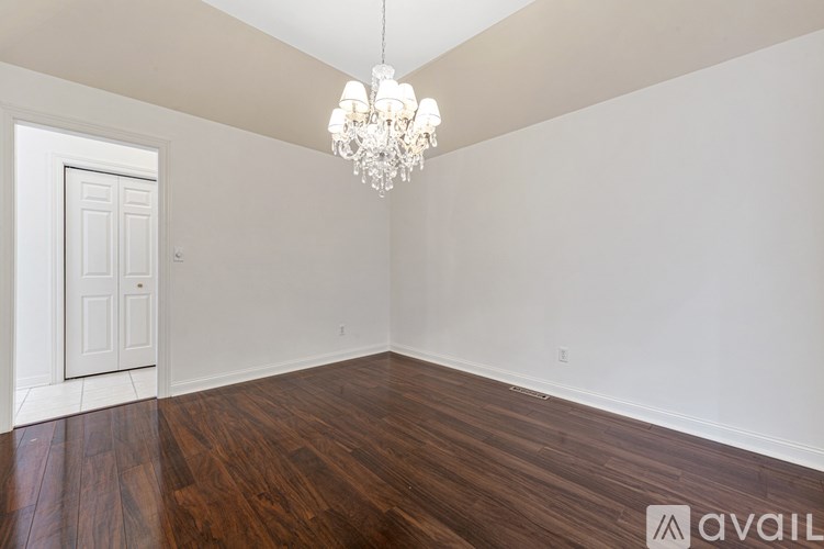A room with a wooden floor and a chandelier hanging from the ceiling.