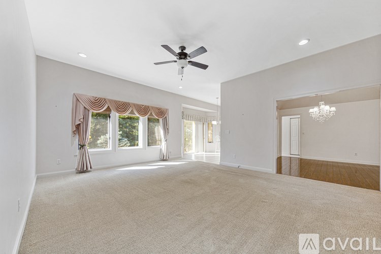 A spacious room with a ceiling fan and carpeted floor.