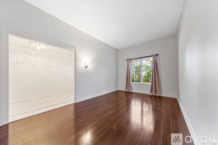 A room with wooden floors and a window with a view of trees.
