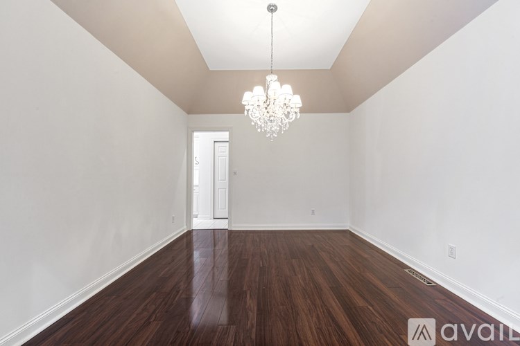 A room with wooden floors and a chandelier hanging from the ceiling.
