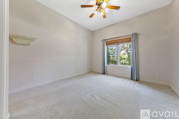 A room with a ceiling fan and a window with curtains.