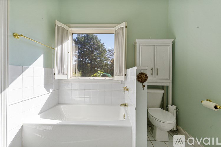 A white bathroom with a window seat and a toilet.