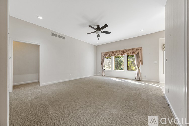 A spacious room with a ceiling fan and carpeted floor.